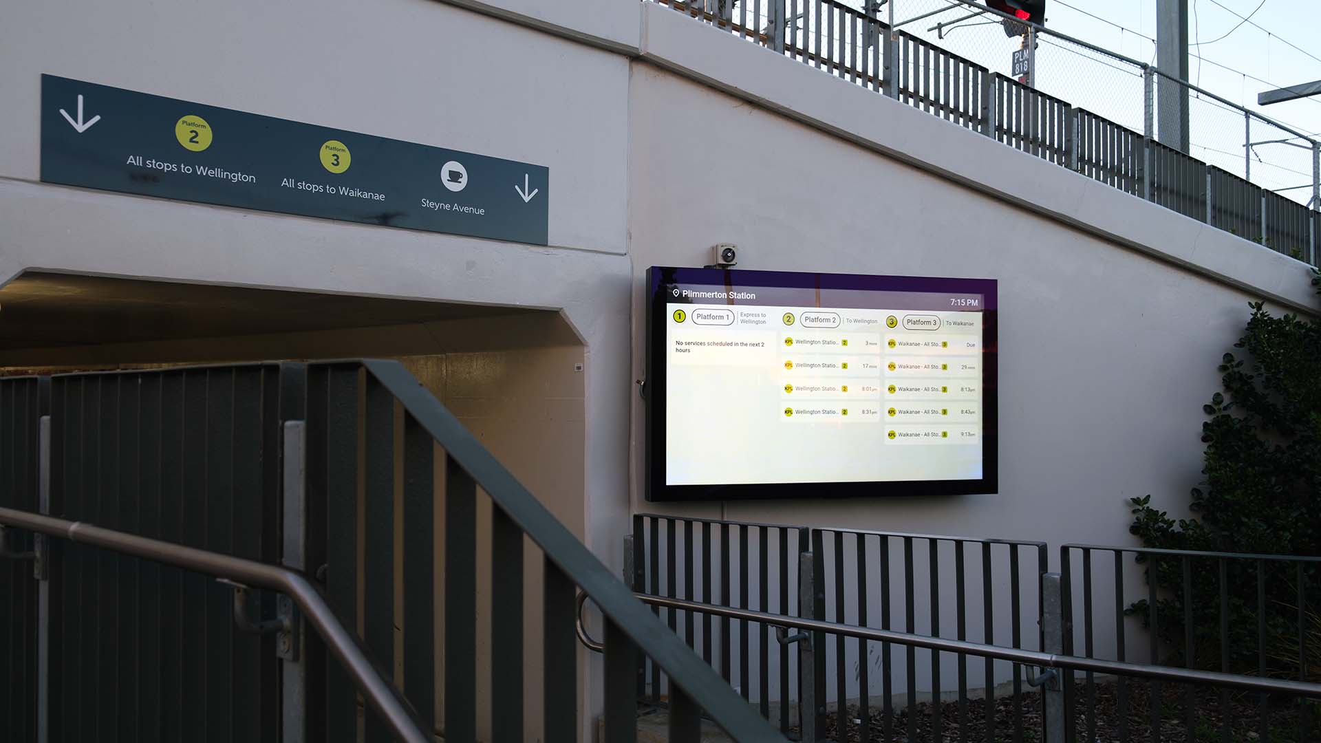 large digital screen at plimmerton station showing train arrival information next to passageway