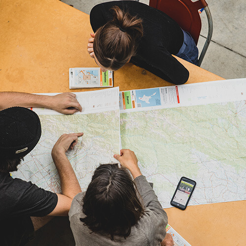 overhead view of three people looking at a map