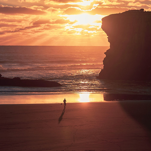 person running along beach sunset