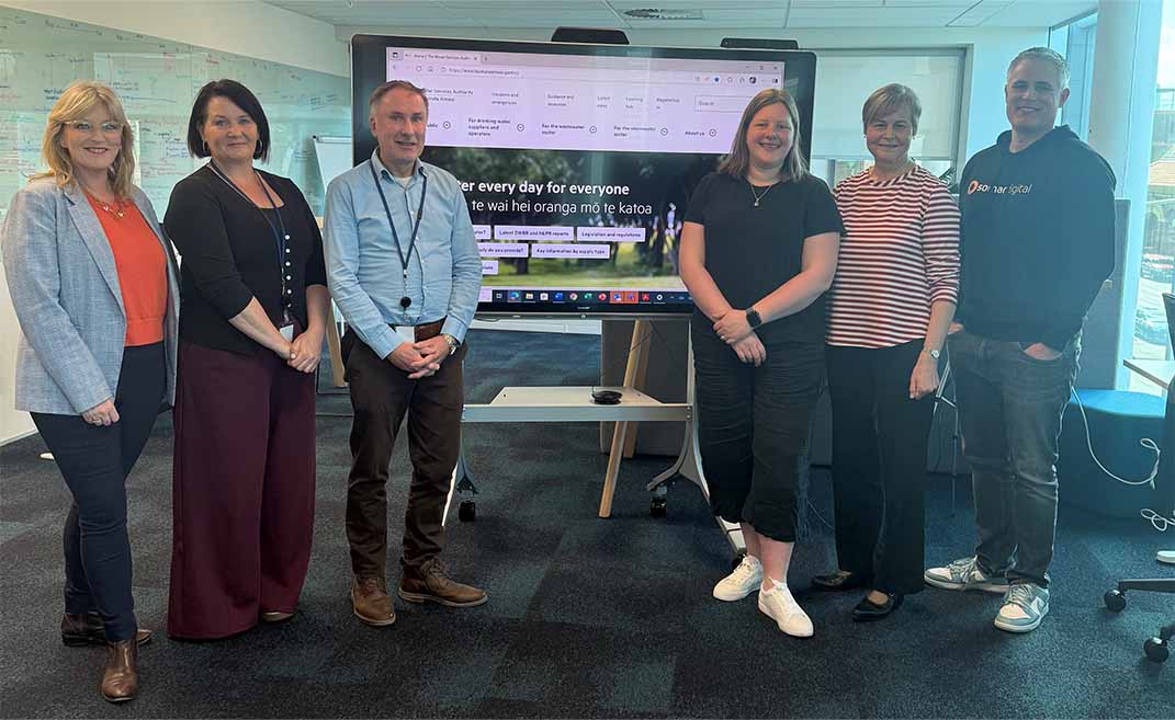 somar and taumata arowai project teams standing infront of screen showing new taumata arowai website